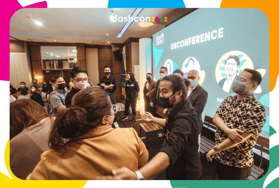 Attendees standing in breakout groups in front of the unconference screen at DashCon 2022